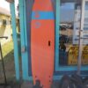 Orange Surfboard propped up against the door