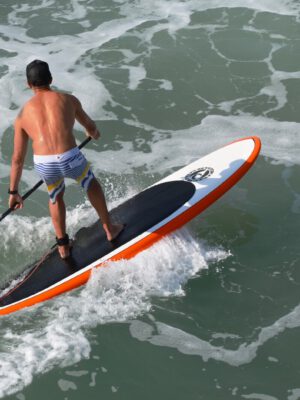 Man Riding Colorful PaddleBoard in Ocean