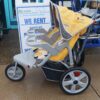 Added Instep Double Baby Jogger. Yellow. In front of sign.